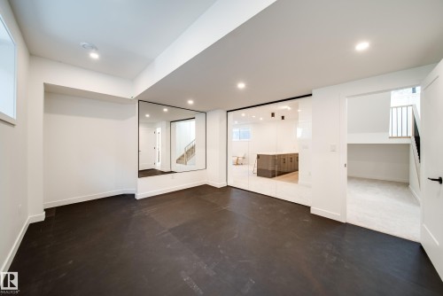 Spacious room with dark flooring, recessed lighting, and a large wall-mounted mirror - 13804 85 Avenue, Edmonton, AB - Indoor Photo Showing Other Room