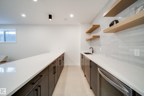 Contemporary wet bar featuring a beverage refrigerator, a black sink with a black faucet, and light wood floating shelves set against a tiled wall - 13804 85 Avenue, Edmonton, AB - Indoor Photo Showing Kitchen