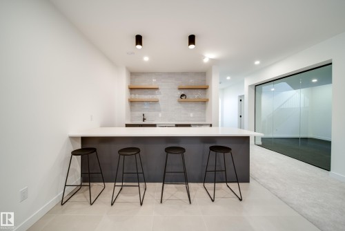 The property features a wet bar with a white countertop, a light gray tile backsplash, and wooden floating shelves - 13804 85 Avenue, Edmonton, AB - Indoor Photo Showing Kitchen