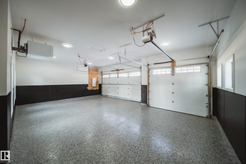The garage features a speckled epoxy floor, two overhead doors with window accents, and recessed ceiling lighting - 13804 85 Avenue, Edmonton, AB - Indoor Photo Showing Garage