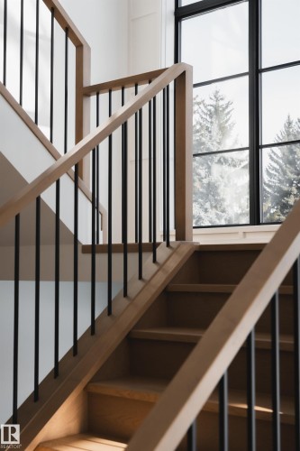 The property features a staircase with light wood banisters and treads, accented by black vertical balusters - 13804 85 Avenue, Edmonton, AB - Indoor Photo Showing Other Room