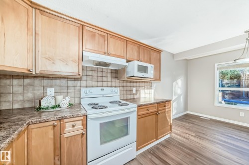 Kitchen featuring white appliances, decorative backsplash, under cabinet range hood, and light brown cabinets - 14 Spring Gate, Spruce Grove, AB - Indoor Photo Showing Kitchen
