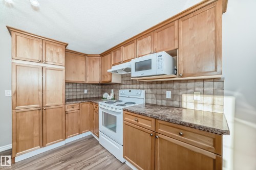 Kitchen featuring white appliances, backsplash, under cabinet range hood, light wood-style flooring, and light brown cabinets - 14 Spring Gate, Spruce Grove, AB - Indoor Photo Showing Kitchen