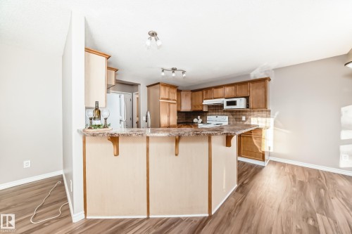 Kitchen with a kitchen breakfast bar, a peninsula, decorative backsplash, and light wood-type flooring - 14 Spring Gate, Spruce Grove, AB - Indoor Photo Showing Kitchen