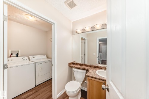 Bathroom with a textured ceiling, vanity, light wood-style floors, and washing machine and clothes dryer - 14 Spring Gate, Spruce Grove, AB - Indoor