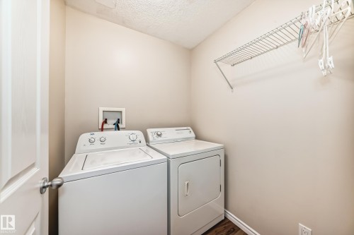 Laundry room featuring a textured ceiling, washing machine and clothes dryer, and dark wood finished floors - 14 Spring Gate, Spruce Grove, AB - Indoor Photo Showing Laundry Room