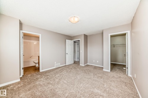 Primary bedroom with a walk in closet, light colored carpet, and ensuite bathroom - 14 Spring Gate, Spruce Grove, AB - Indoor