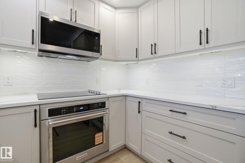 Kitchen featuring white shaker-style cabinetry with black hardware, white countertops, and a white subway tile backsplash - 516 260 Bellerose Dr, St. Albert, AB - Indoor Photo Showing Kitchen With Upgraded Kitchen