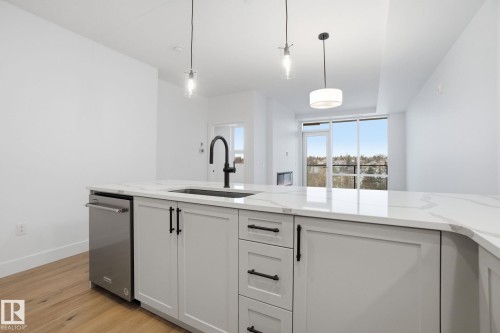 Kitchen featuring light wood flooring, white cabinetry with dark hardware, a stainless steel dishwasher, and white countertops - 516 260 Bellerose Dr, St. Albert, AB - Indoor Photo Showing Kitchen With Upgraded Kitchen