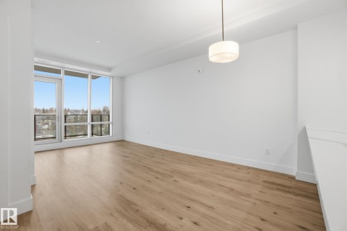 This bright room features a neutral color palette, hardwood flooring, and large windows that provide a view of the surrounding area - 516 260 Bellerose Dr, St. Albert, AB - Indoor Photo Showing Other Room