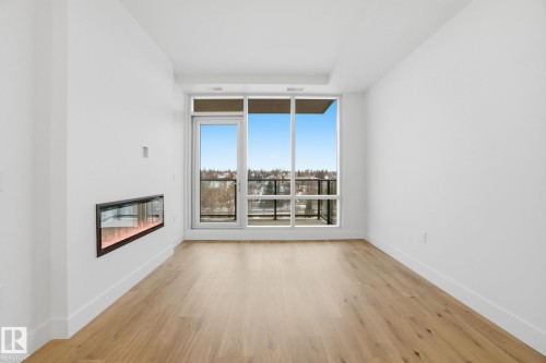 The living space features hardwood floors, a modern linear fireplace, and floor-to-ceiling windows with balcony access - 516 260 Bellerose Dr, St. Albert, AB - Indoor With Fireplace