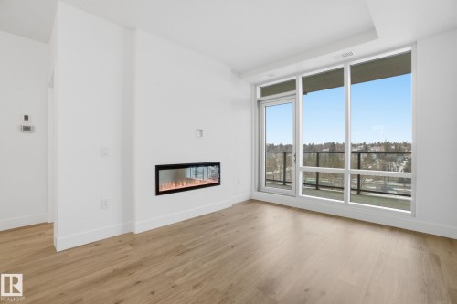 Living area featuring light wood flooring, a linear fireplace, and expansive windows with a view - 516 260 Bellerose Dr, St. Albert, AB - Indoor Photo Showing Living Room With Fireplace
