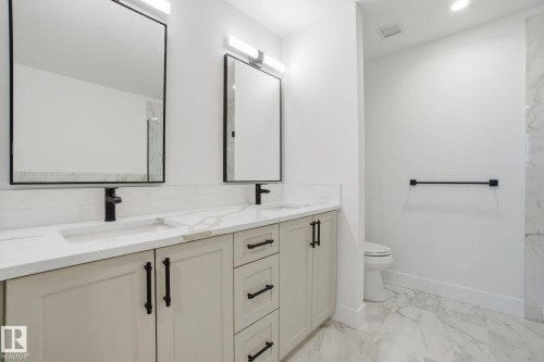 The bathroom features a double vanity with light-colored cabinetry, white countertops, and black hardware - 516 260 Bellerose Dr, St. Albert, AB - Indoor Photo Showing Bathroom