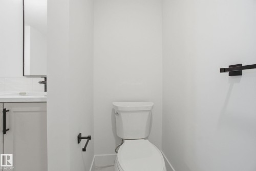 Bathroom with a white toilet, white vanity with black hardware, and a black framed mirror - 516 260 Bellerose Dr, St. Albert, AB - Indoor Photo Showing Bathroom