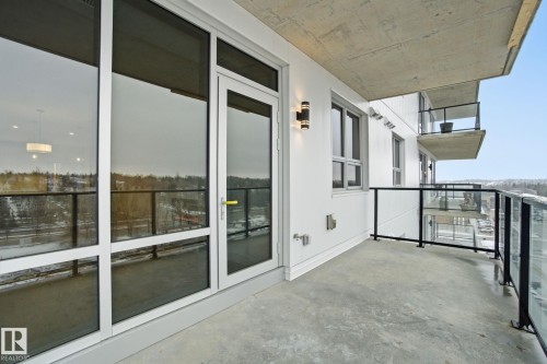 The balcony features a concrete floor, glass and metal railings, and an exterior wall sconce - 516 260 Bellerose Dr, St. Albert, AB - Outdoor With Balcony With Exterior