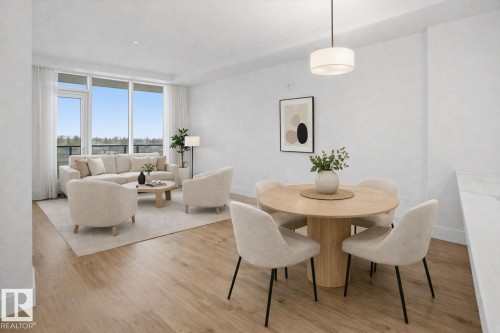 This open-concept living area features light wood flooring, a dining space with a pendant light fixture, and a living area with large windows providing natural light - 516 260 Bellerose Dr, St. Albert, AB - Indoor Photo Showing Dining Room