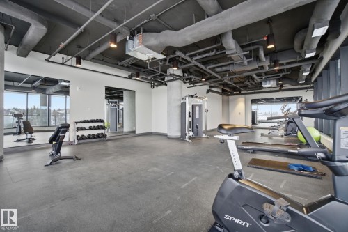 The property features a dedicated fitness area with gym equipment, large windows, and a mirrored wall - 516 260 Bellerose Dr, St. Albert, AB - Indoor Photo Showing Gym Room