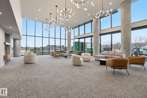 Spacious common area featuring full-height windows, contemporary light fixtures, and carpeted flooring - 516 260 Bellerose Dr, St. Albert, AB - Indoor Photo Showing Other Room