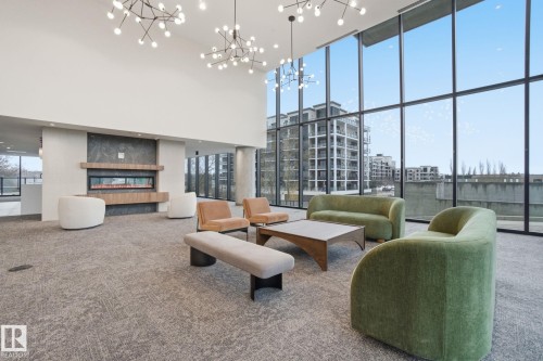 The property features a spacious common area with high ceilings, large windows, and contemporary light fixtures - 516 260 Bellerose Dr, St. Albert, AB - Indoor Photo Showing Other Room
