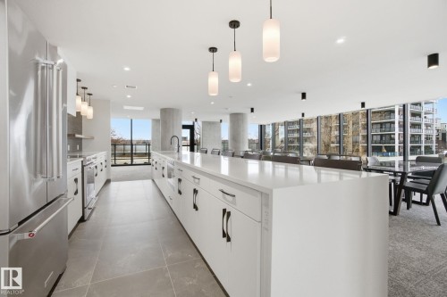 This modern kitchen features stainless steel appliances, a long island with a sink, and pendant lighting - 516 260 Bellerose Dr, St. Albert, AB - Indoor Photo Showing Kitchen With Upgraded Kitchen