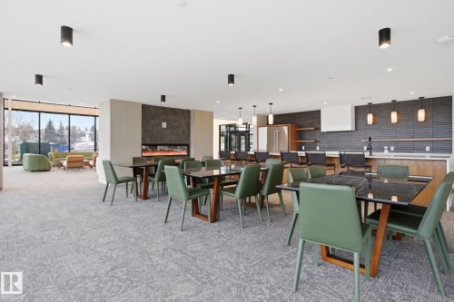 Spacious communal area featuring patterned carpeting, a modern fireplace, and large windows providing natural light - 516 260 Bellerose Dr, St. Albert, AB - Indoor