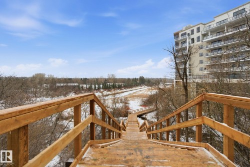 The property features a multi-story building with balconies, set against a backdrop of a natural landscape - 516 260 Bellerose Dr, St. Albert, AB - Outdoor With Balcony
