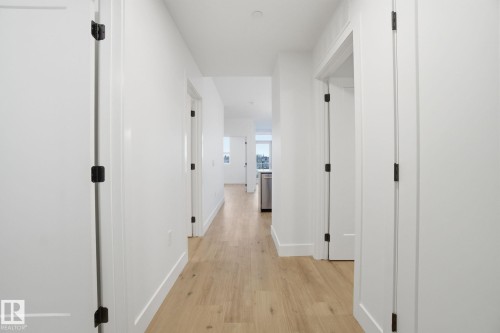 Hallway featuring light-colored flooring, white walls, and white doors with dark hardware - 516 260 Bellerose Dr, St. Albert, AB - Indoor Photo Showing Other Room