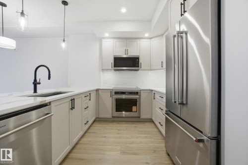 The kitchen features light-toned cabinetry, stainless steel appliances, a white subway tile backsplash, and a large sink with a matte black faucet - 516 260 Bellerose Dr, St. Albert, AB - Indoor Photo Showing Kitchen With Stainless Steel Kitchen With Upgraded Kitchen