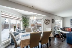 The dining area features wood flooring, large windows, and a contemporary chandelier - 