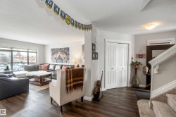Spacious living area featuring large windows, wood-look flooring, and a closet with bi-fold doors - 