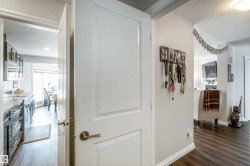 The property features a white paneled interior door with a brushed nickel handle, leading into a space with dark wood-style flooring - 