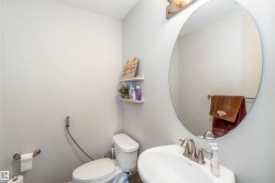 Bathroom featuring light grey walls, a white toilet, and a white pedestal sink with a brushed nickel faucet - 