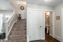 Welcoming entry with a carpeted staircase and hardwood flooring - 
