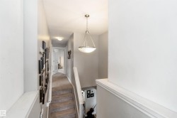 Carpeted staircase and hallway with light-colored walls and a ceiling light fixture - 