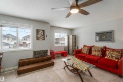 Living area featuring light colored walls, windows, and a ceiling fan with integrated lighting - 