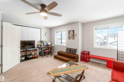 This versatile room features carpeted flooring, a ceiling fan with integrated lighting, and multiple windows allowing for natural light - 