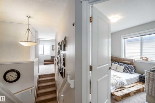 View of a carpeted staircase with a hanging light fixture and a room with a window - 12232 167B Avenue, Edmonton, AB - Indoor