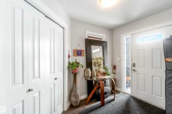 Entryway featuring a white paneled door with a sidelight and transom window, a closet with bifold doors, and dark flooring - 