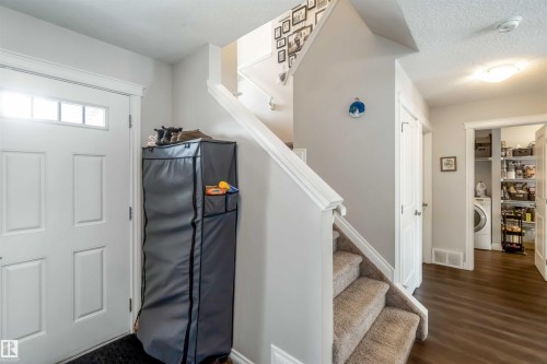 The property features a front entrance with a white paneled door, a staircase with carpeted treads, and wood flooring in the hallway - 12232 167B Avenue, Edmonton, AB - Indoor Photo Showing Other Room