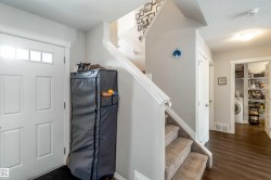 The property features a front entrance with a white paneled door, a staircase with carpeted treads, and wood flooring in the hallway - 