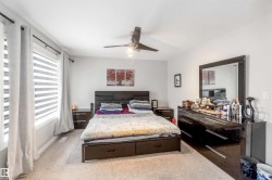 Bedroom featuring light-colored carpeting, a window with blinds and curtains, and a ceiling fan - 