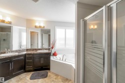 This bathroom features a double vanity with dark cabinetry, dual sinks, and expansive mirrors - 