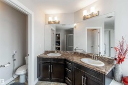 Bathroom featuring a double vanity with dark wood cabinetry, a light-colored countertop, and two mirrors with overhead lighting - 