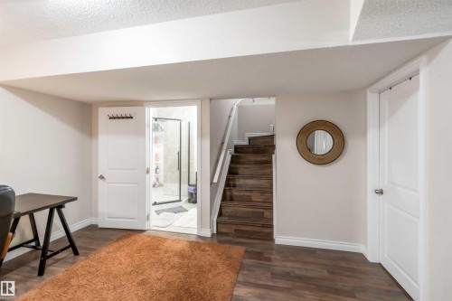This interior space features dark wood flooring, light-colored walls, and a staircase with dark wood treads and white risers - 12232 167B Avenue, Edmonton, AB - Indoor Photo Showing Other Room