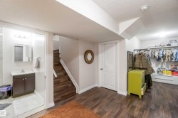 The property features wood flooring, a staircase with wood treads, and white walls - 