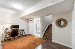 This inviting area features dark wood flooring, light-colored walls, and a staircase with a white handrail - 