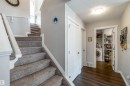 Inviting entryway featuring dark wood-style flooring, a staircase with carpeted treads and white banisters, and a laundry area with a washing machine and shelving - 12232 167B Avenue, Edmonton, AB  - Indoor Photo Showing Other Room 