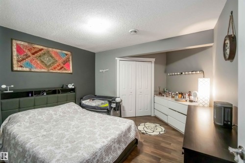 This bedroom features wood-look flooring and a closet with bi-fold doors - 12232 167B Avenue, Edmonton, AB - Indoor Photo Showing Bedroom