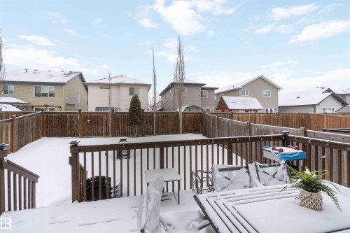 The property features a wooden deck with a railing overlooking a snow-covered yard, enclosed by a wooden fence - 12232 167B Avenue, Edmonton, AB - Outdoor With Deck Patio Veranda