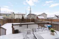 The property features a wooden deck with a railing overlooking a snow-covered yard, enclosed by a wooden fence - 